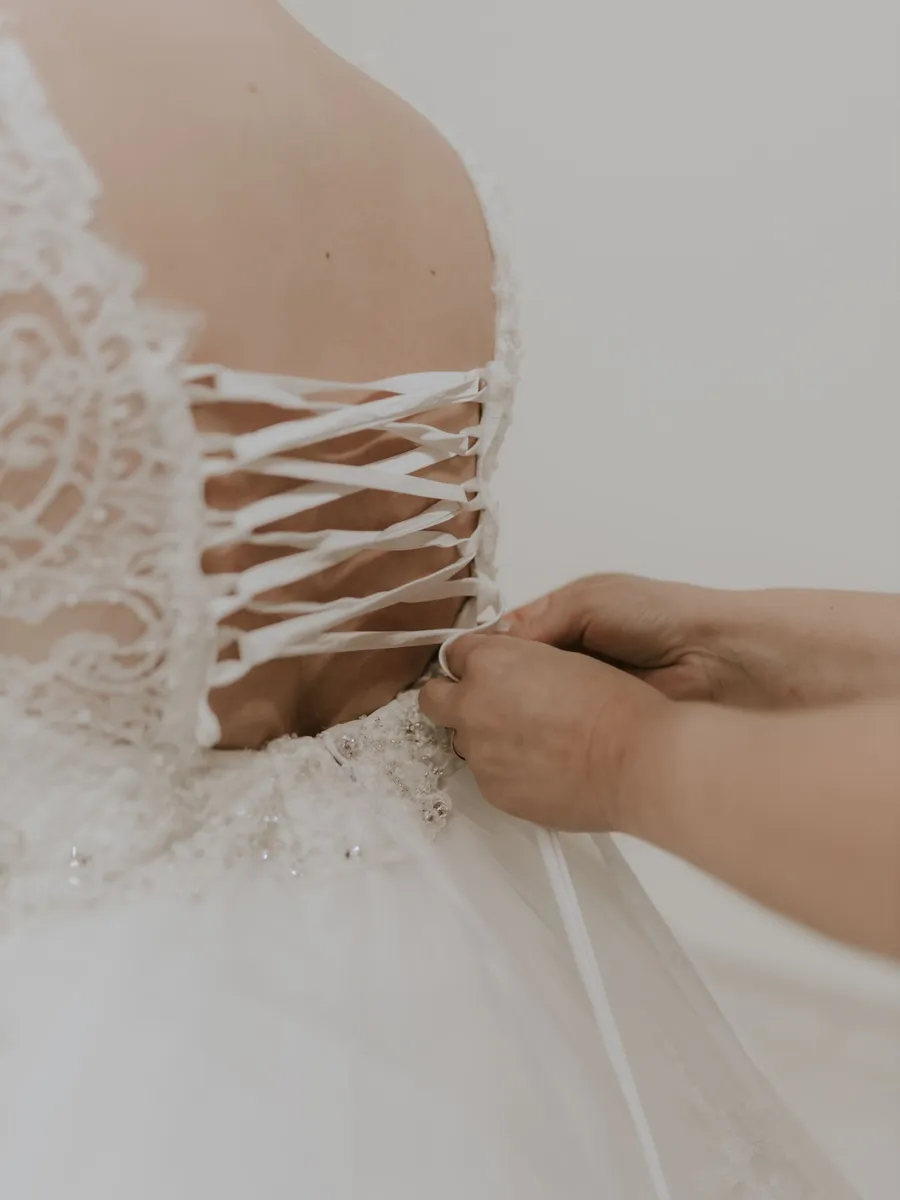 Hands lace the back of a bodice during a fitting