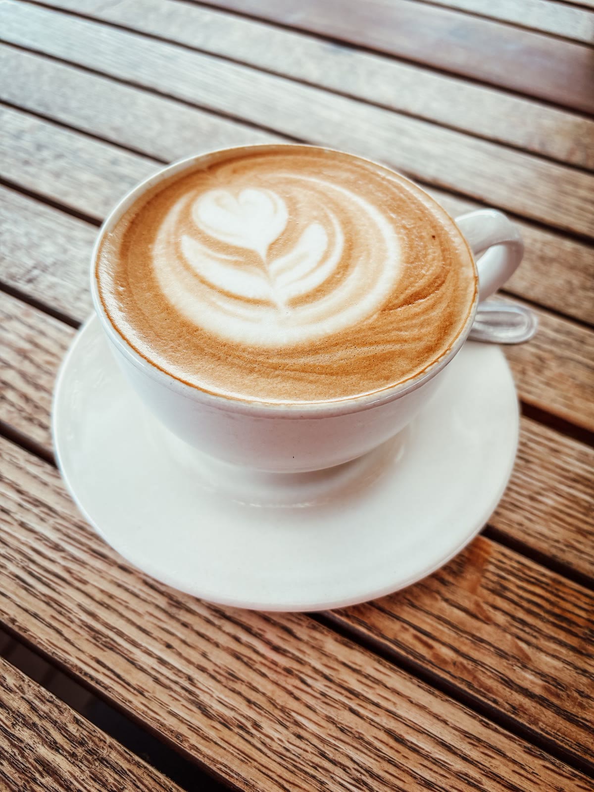 Cappuccino with latte art on a sunny wooden table