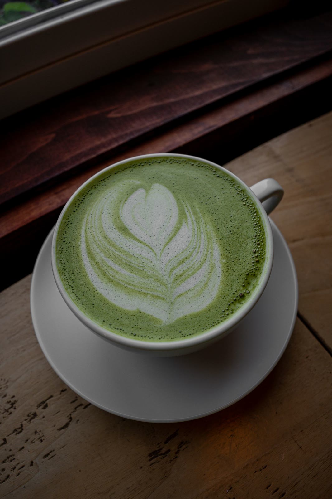 Matcha latte with latte art on a warm wooden table