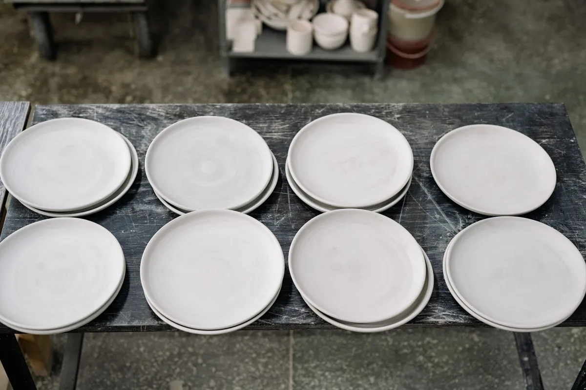 Freshly glazed plates drying on a workshop table