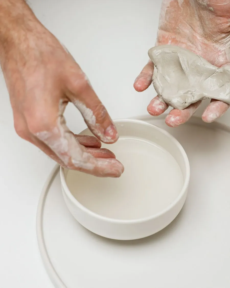 Hands shaping a bowl from wet clay