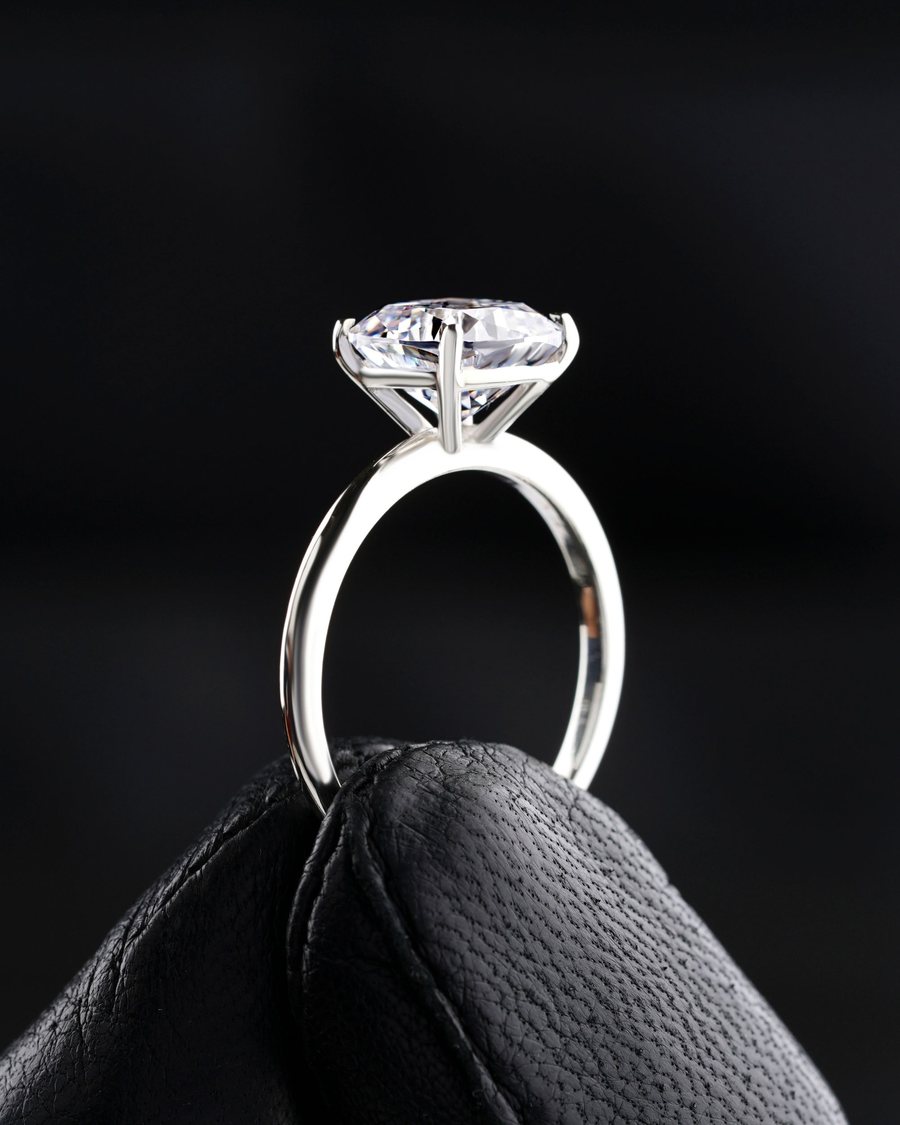 White gold solitaire ring held up on black leather