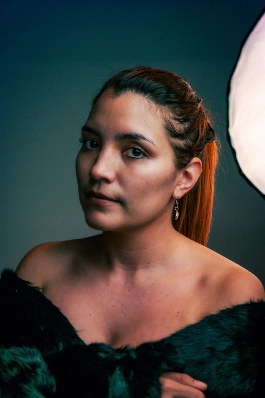 Portrait of a woman with a teal backdrop and a soft light
