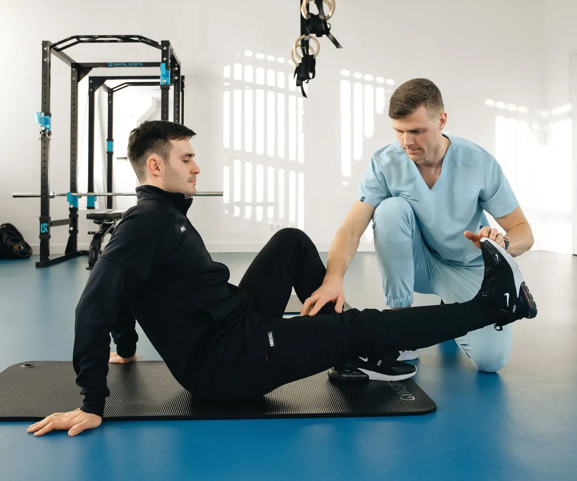 Therapist stretching a patient's leg on the clinic training floor