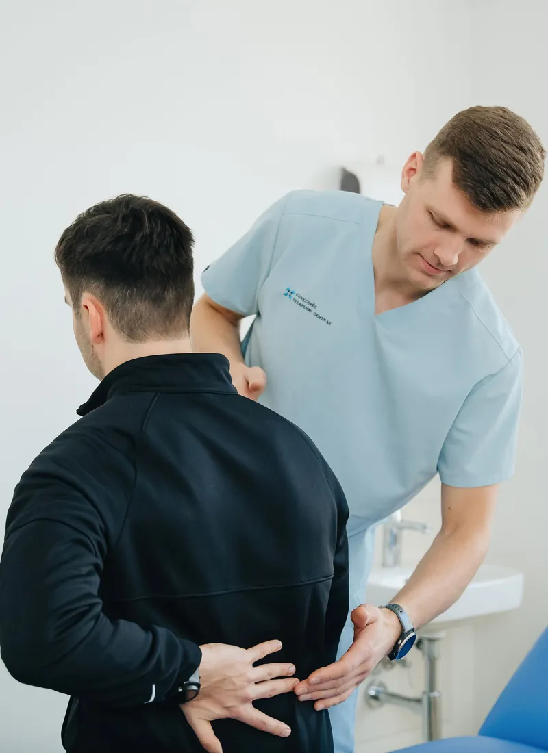 Therapist assessing a standing patient's lower back
