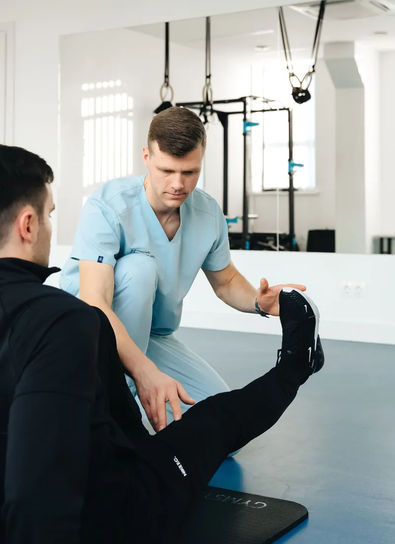 Patient doing a leg raise with a therapist on the training floor
