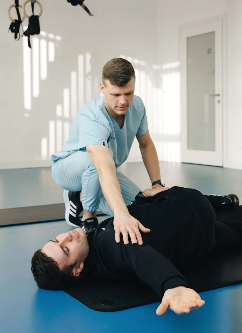 Therapist guiding a patient through a stretch on the training floor
