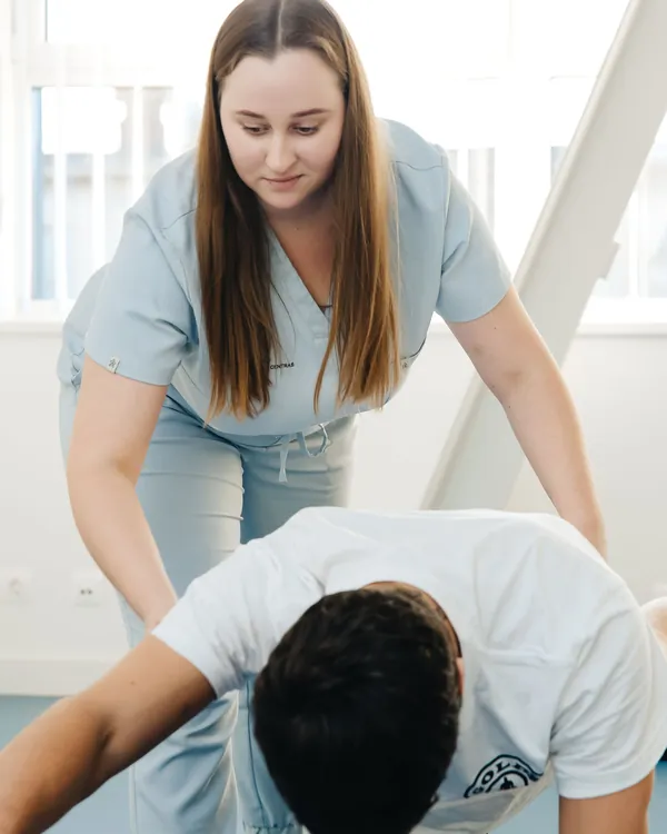 Therapist supporting a patient's upper back during an exercise