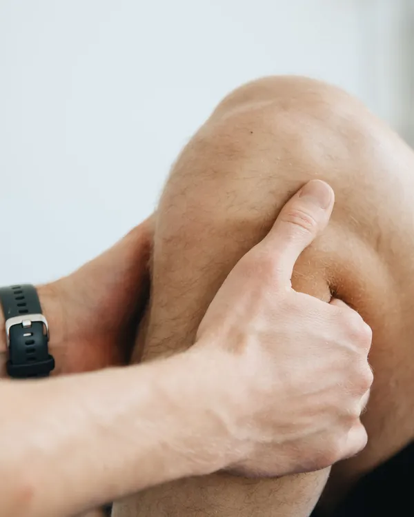 Therapist applying manual pressure above a patient's knee