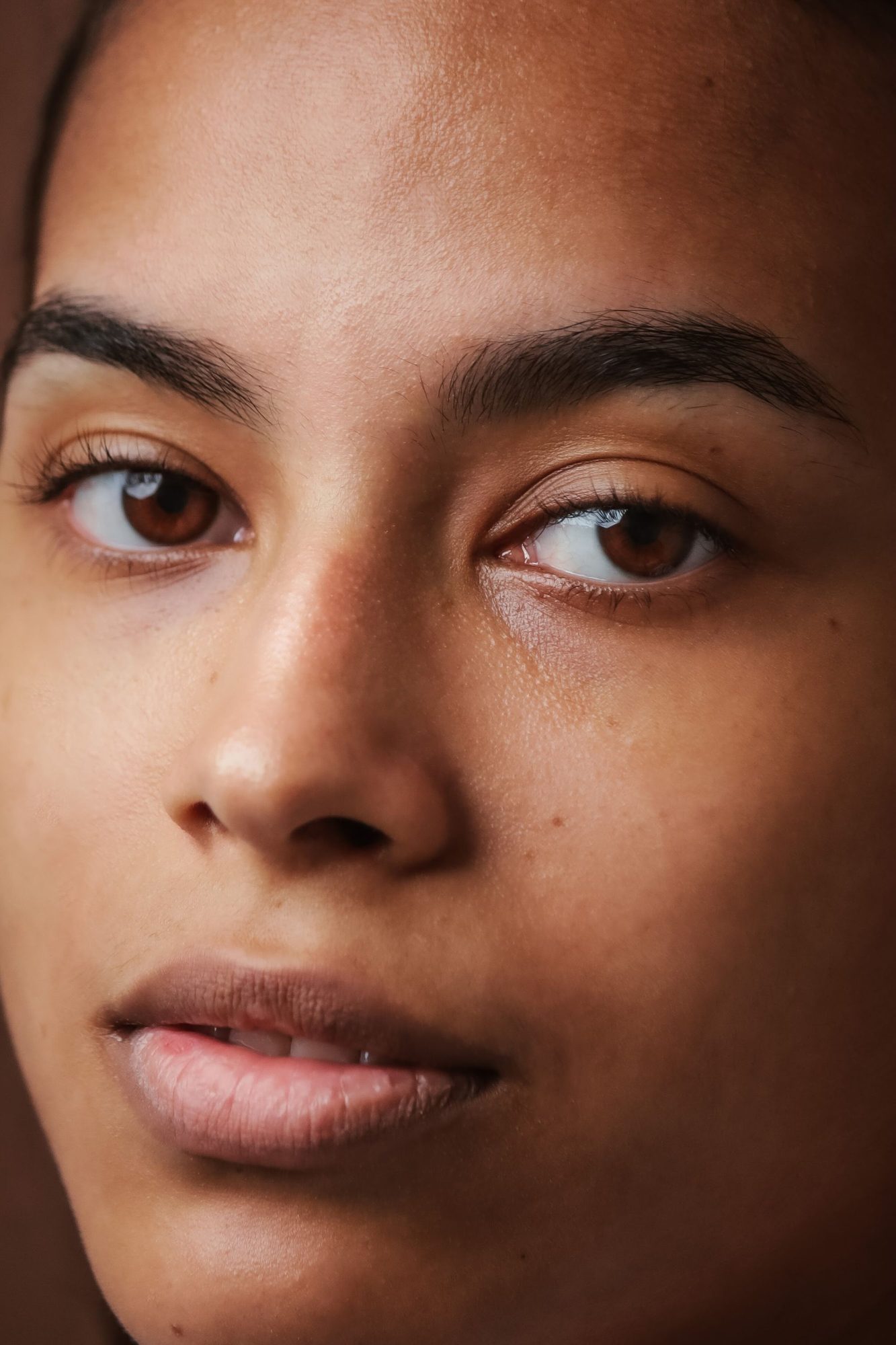 A calm face with full natural brows, looking at the camera