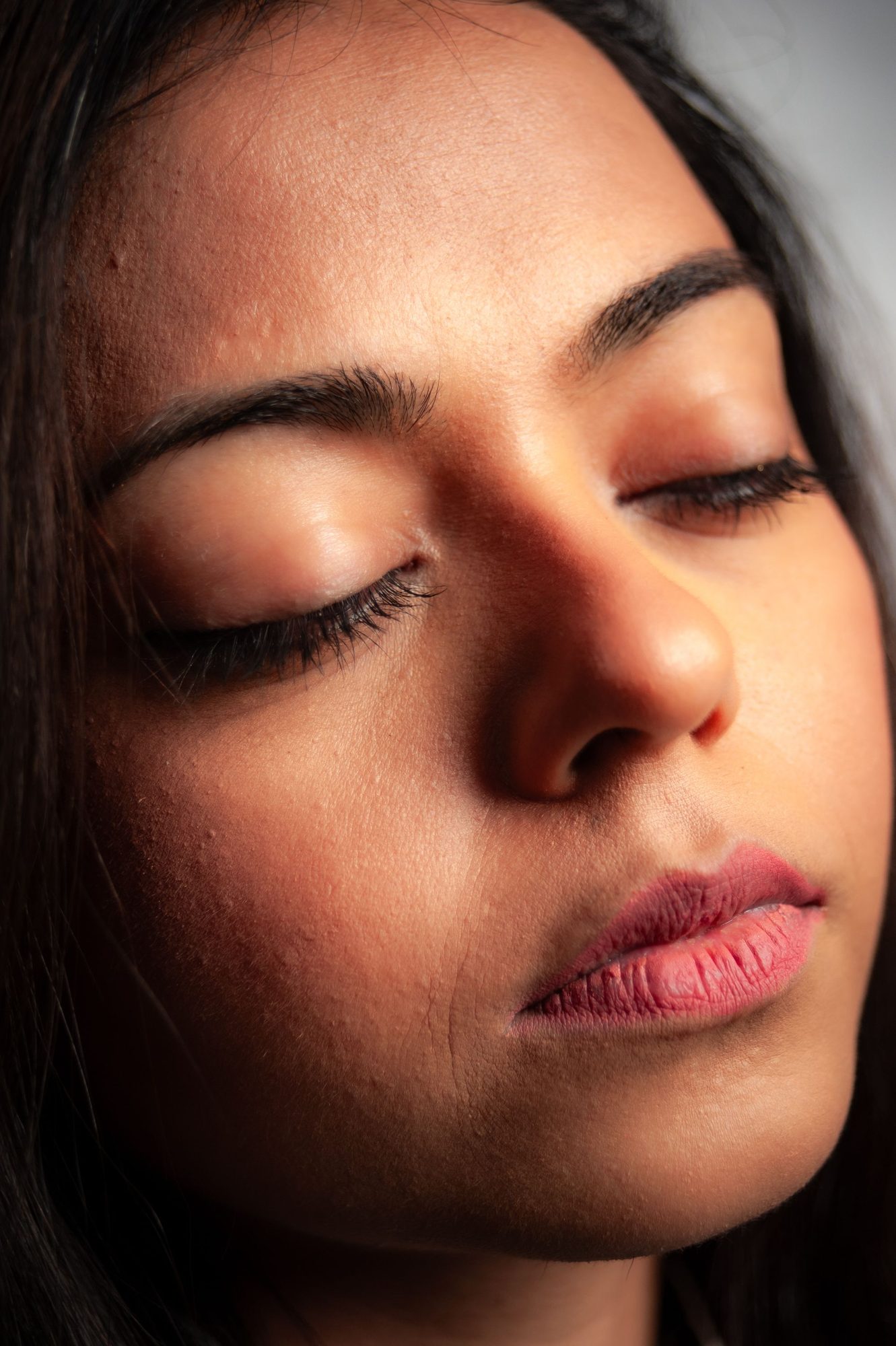A calm face, eyes closed, warm skin, full natural brows