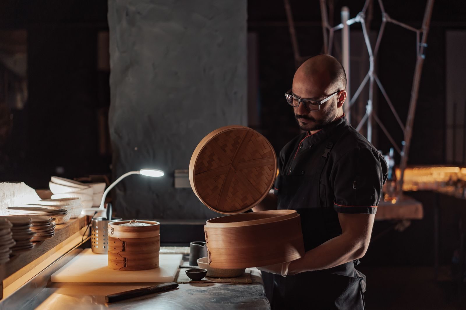 Chef opening a bamboo steamer at the pass