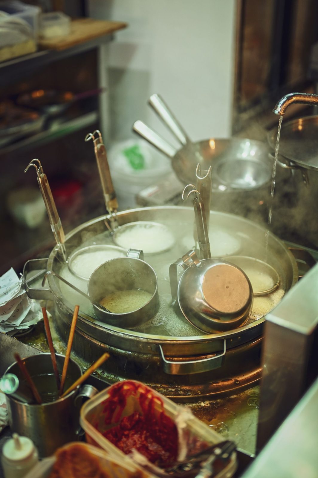Noodle baskets resting in a steaming pot in the kitchen