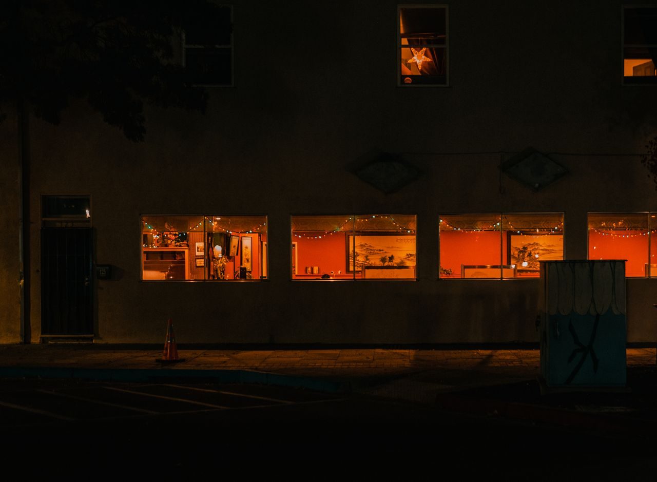 Warm lit restaurant windows glowing on a quiet street at night